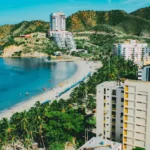 Vista aérea de playa tropical con edificios modernos, palmeras y mar azul en Colombia