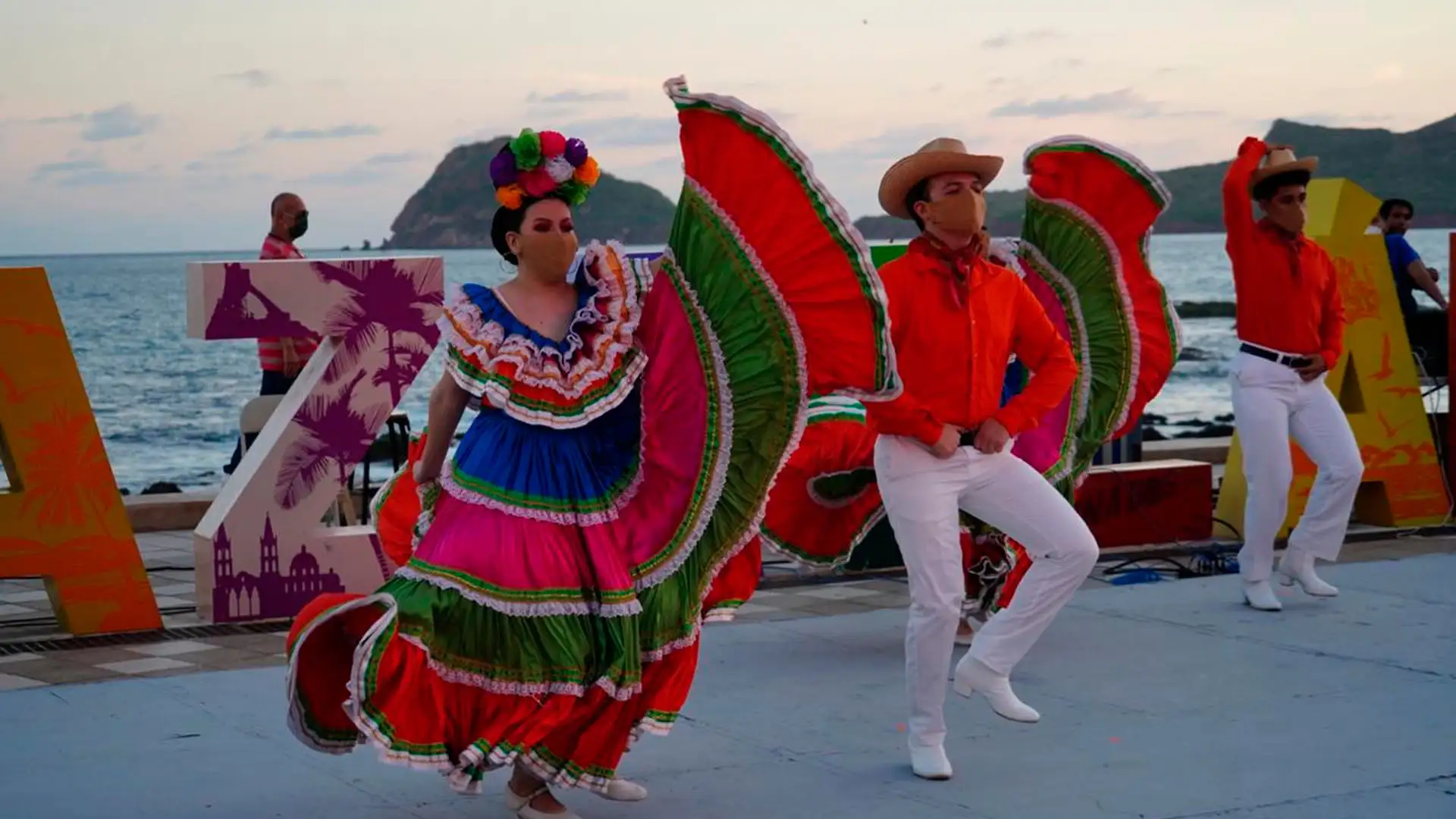 Bailarines con trajes típicos de México interpretando danza folklórica frente al malecón de Mazatlán al atardecer