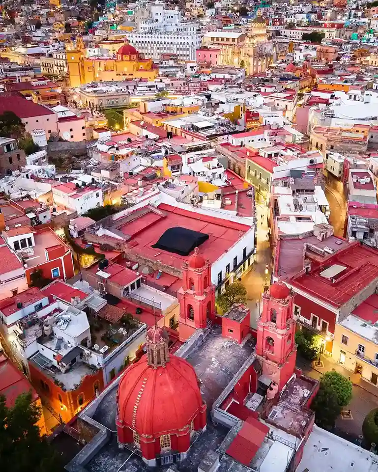 Vista aérea del colorido centro histórico de Guanajuato al atardecer con sus iglesias y calles coloniales