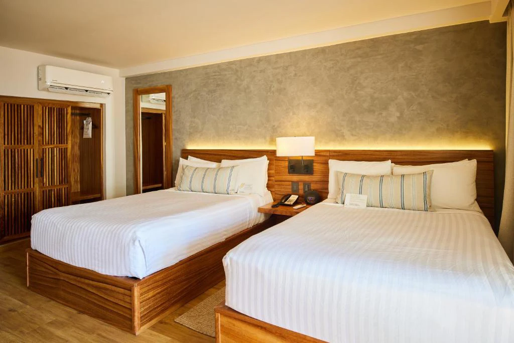 Habitación doble moderna con dos camas, decoración cálida y estilo contemporáneo en el Hotel Emporio Mazatlán México.