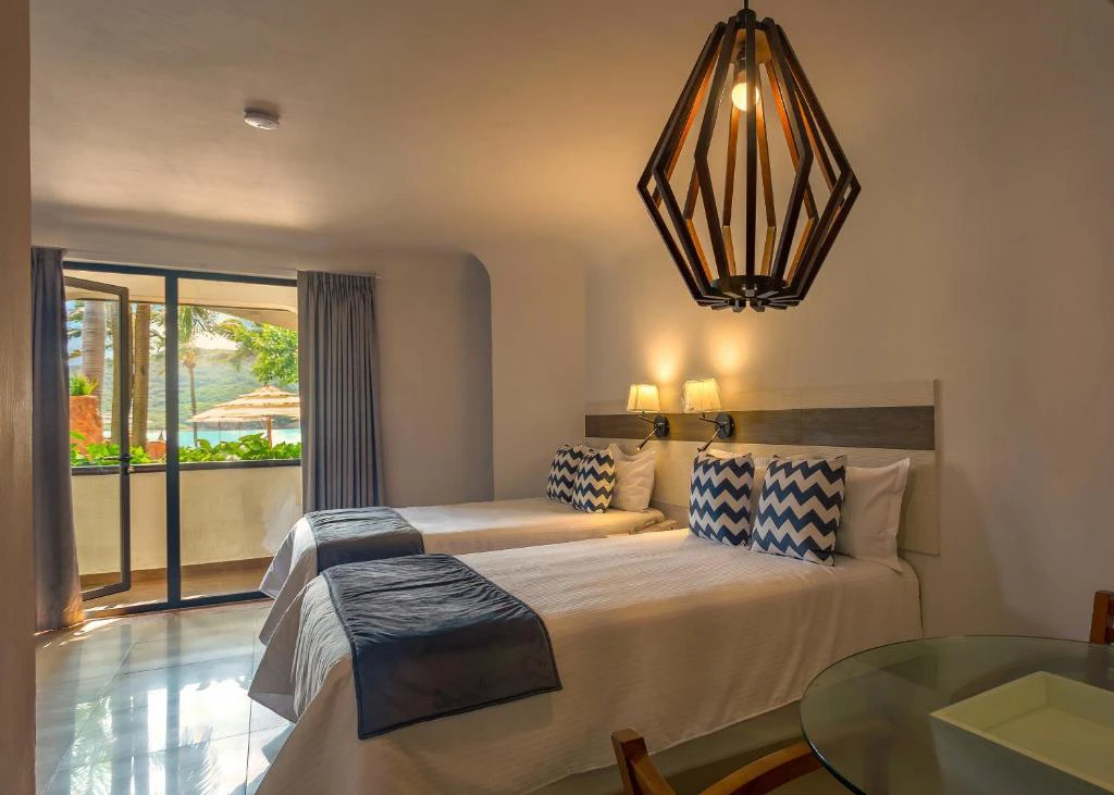 Habitación doble moderna con vista al océano, decoración cálida y balcón privado en Mazatlán, México.