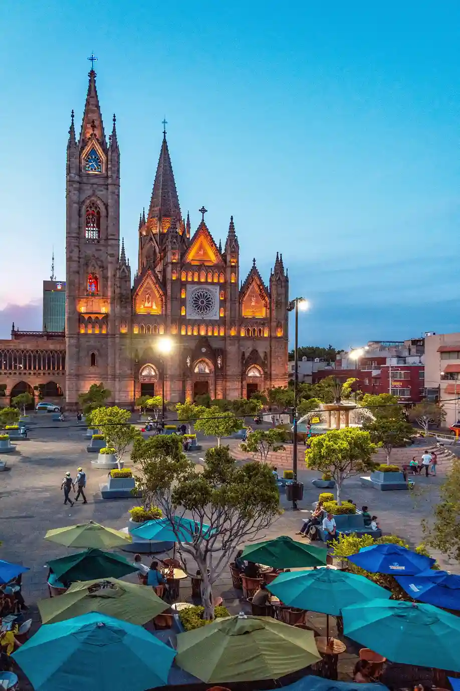 Templo Expiatorio iluminado al atardecer en Guadalajara, Jalisco, con terrazas y visitantes en la plaza