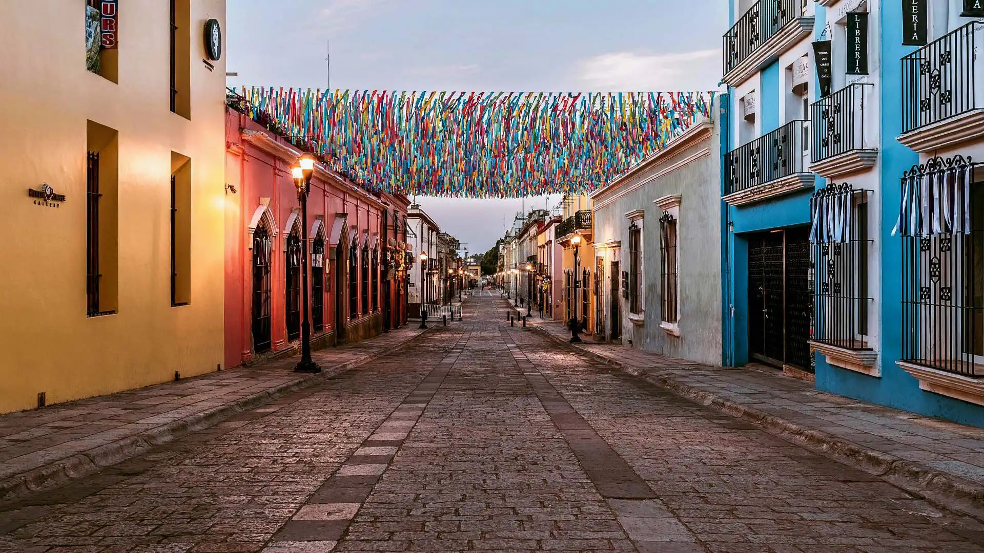 Calle empedrada del centro histórico de Oaxaca decorada con cintas de colores y fachadas coloniales