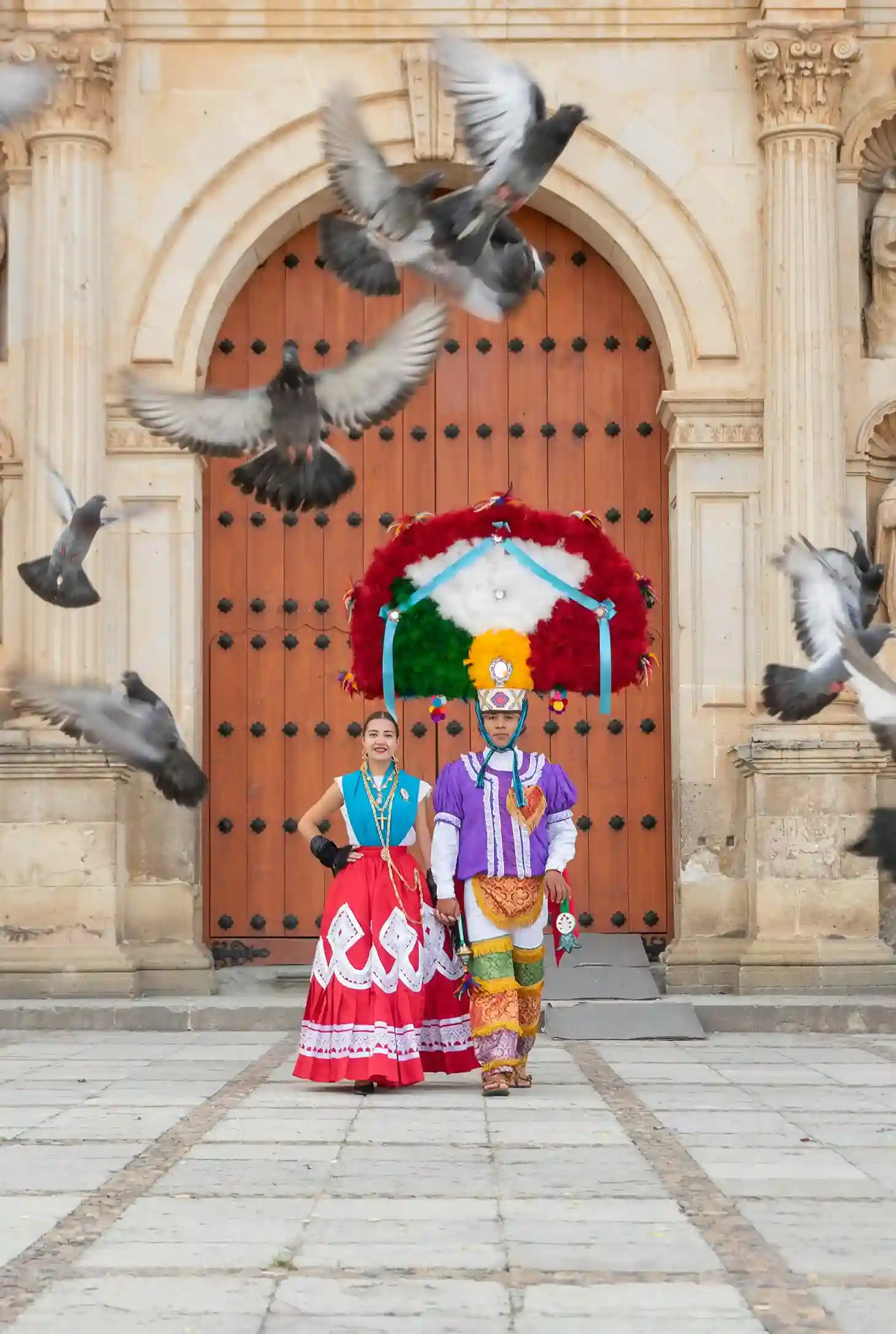 Pareja con trajes típicos de Oaxaca frente a la Catedral de Santo Domingo, representando la Danza de la Pluma