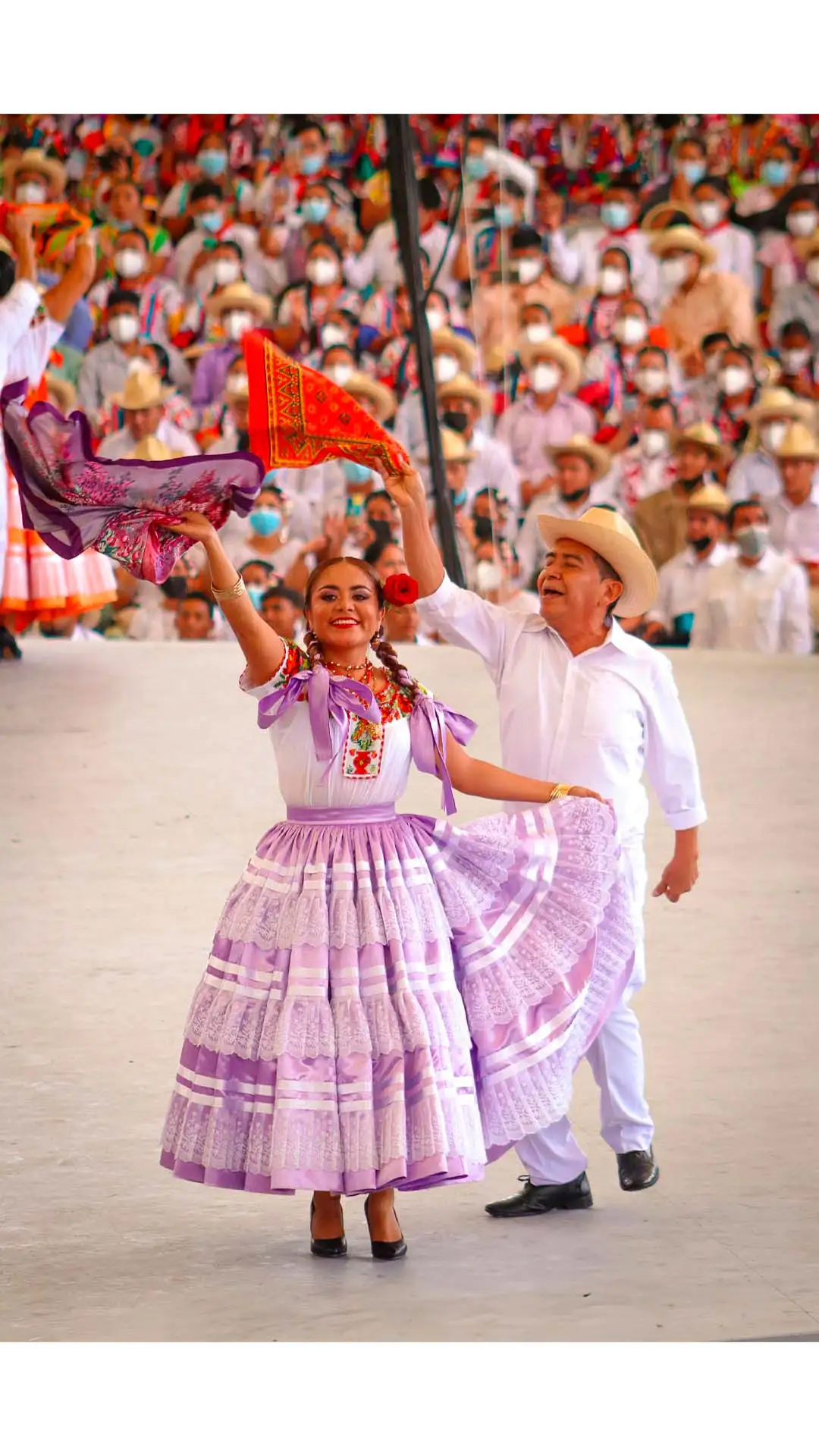 Pareja bailando en la Guelaguetza de Oaxaca con trajes típicos y pañuelos coloridos