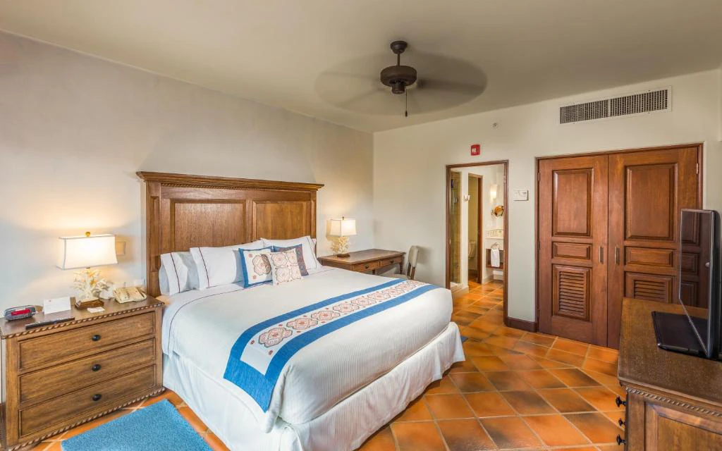 Suite elegante con cama king size, decoración rústica y detalles artesanales en hotel de Los Cabos, México.