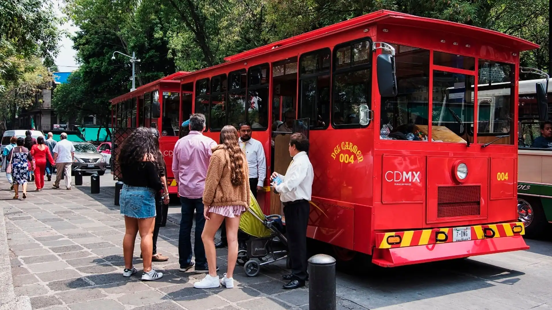 Turistas abordando tranvía rojo en la Ciudad de México durante un recorrido turístico
